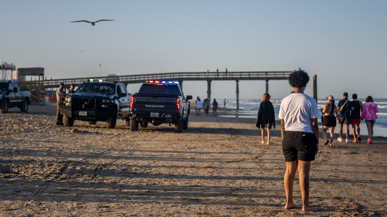 Police vehicles on the beach near partygoers in South Padre Island