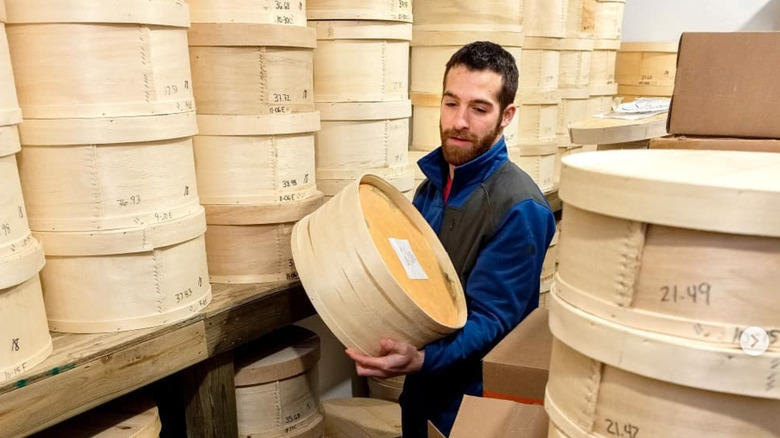Man holding wheel of cheese in large basket