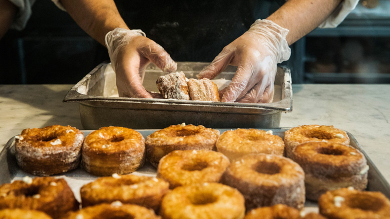a chef rolls two cronuts in maple sugar