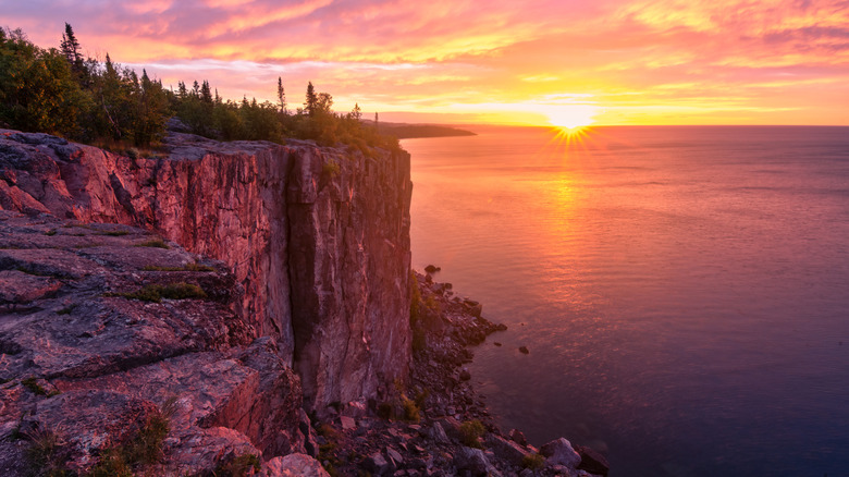Sunrise over lake and tall rocky cliffs