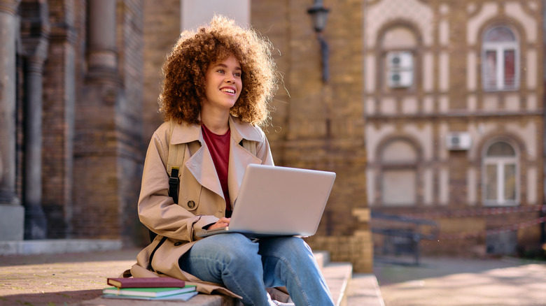Woman sitting on building steps with laptop