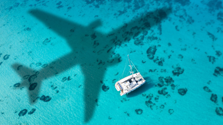 Airplane shadow over a boat in turquoise tropical water
