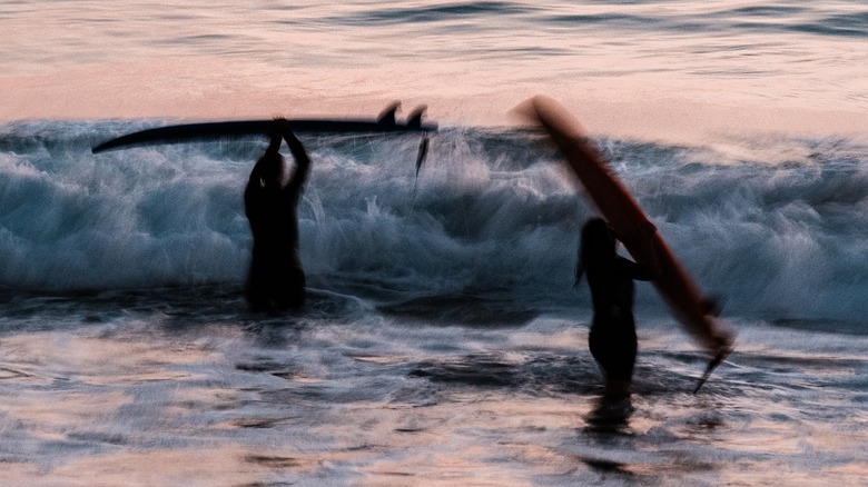 Surfers lifting up their surfboards over the waves of Taghazout