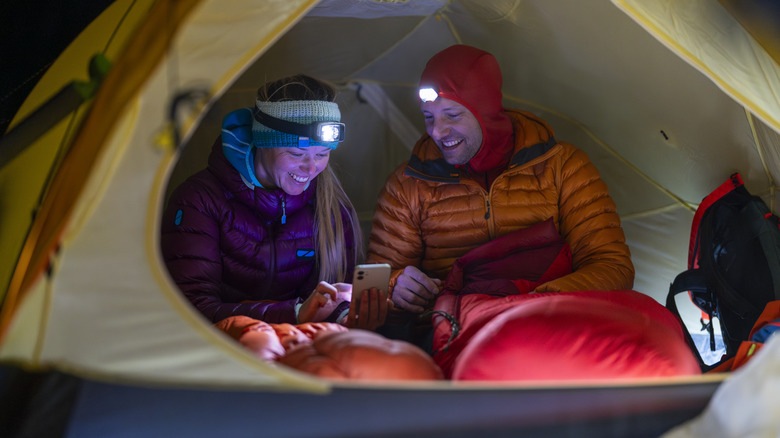 Couple in tent with sleeping bags and headlamps