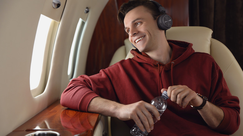 man holds water bottle on airplane
