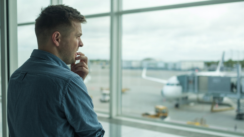 Man nervously looking out the window at the airport