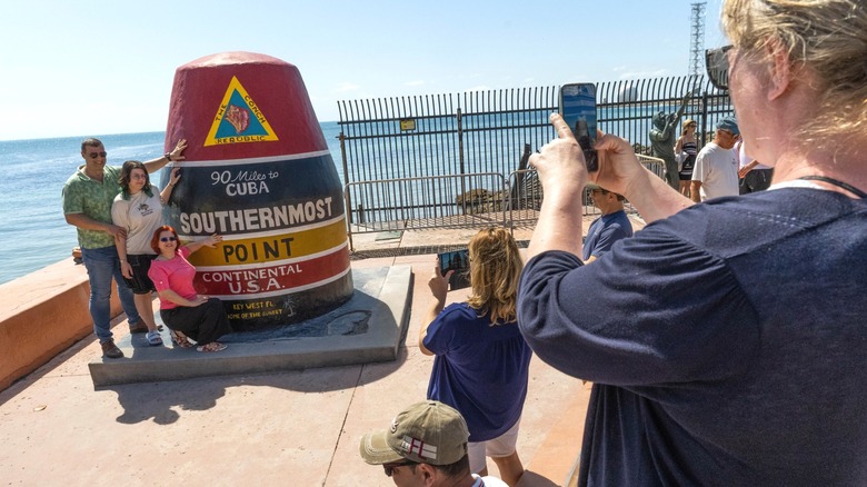 People taking pictures in front of the Southernmost Point Buoy in Key West