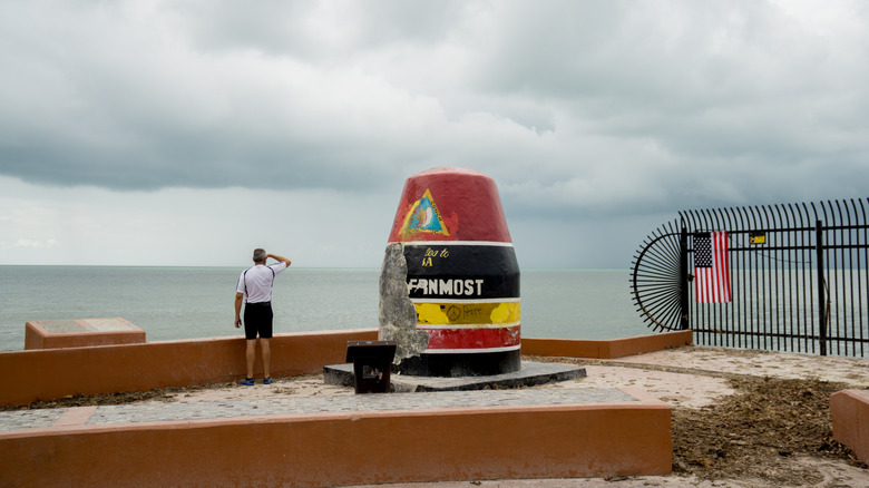 A man looking out to the water next to the damaged Southernmost Point buoy