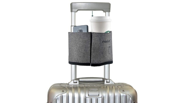 Travel cup holder installed on the handle of a suitcase