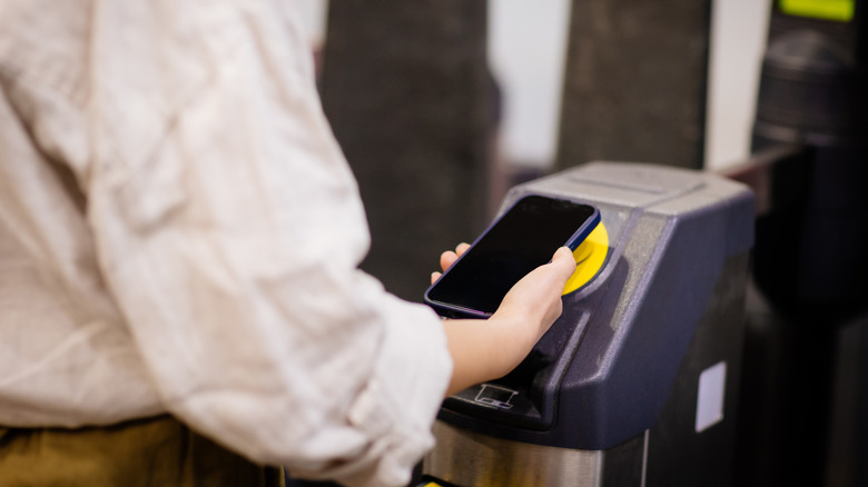 A person using smartphone to tap onto the London Tube machine.