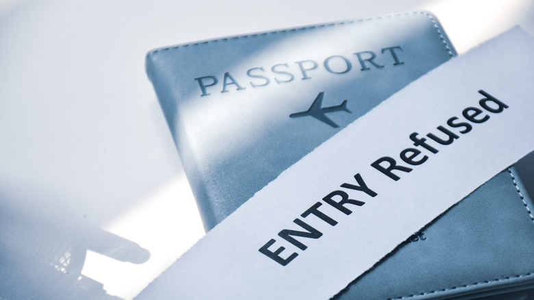 A passport with a torn scrap of paper on top that says 