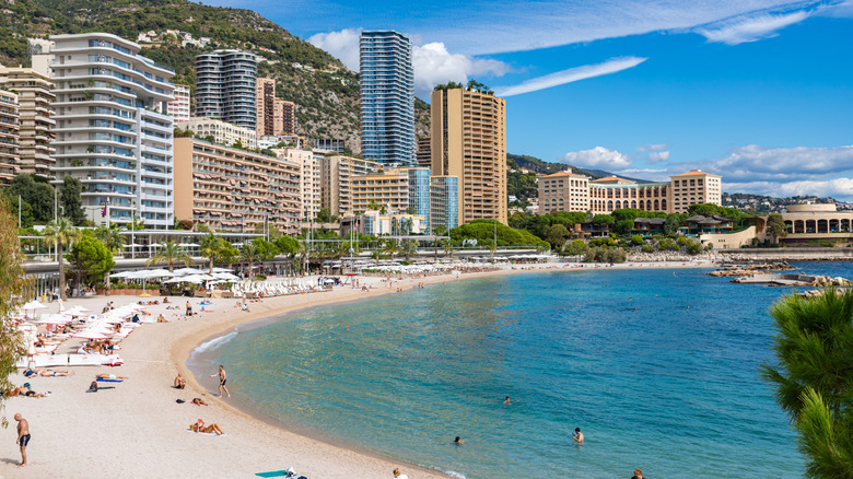 People sunbathing and swimming at Larvotto Beach in Monaco on a sunny day