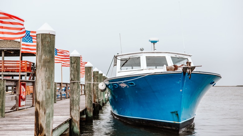 Blue boat docked in Crisfield port, with US flags in background