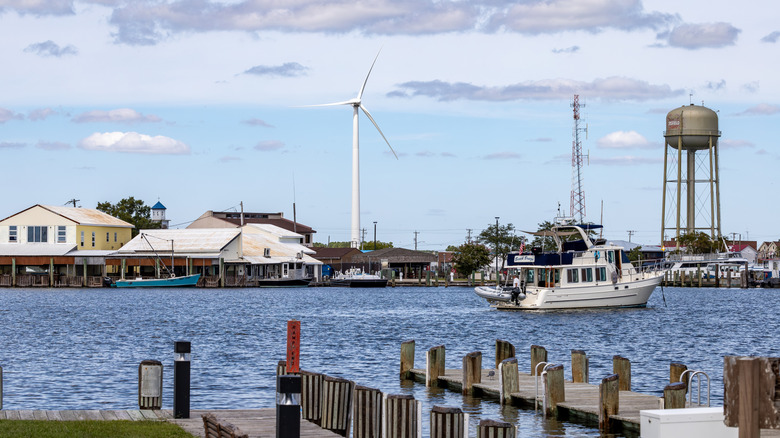 Boat sailing past wind turbine and water tower at Crisfield waterfront