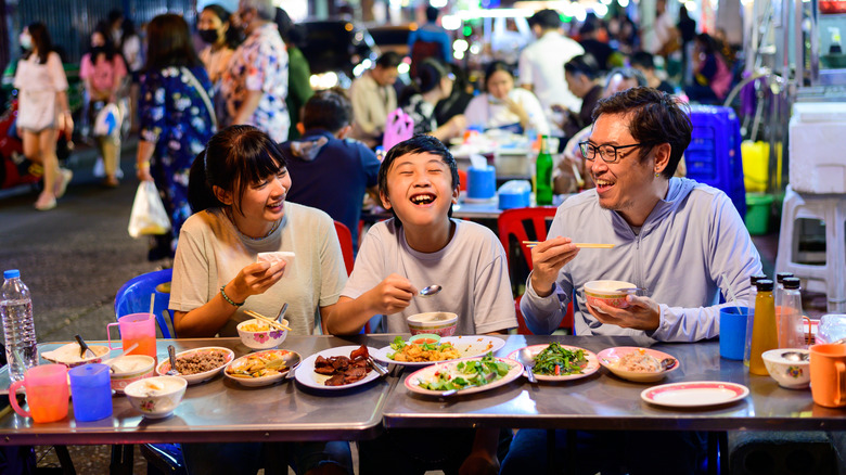 People enjoying street food in Thailand and smiling