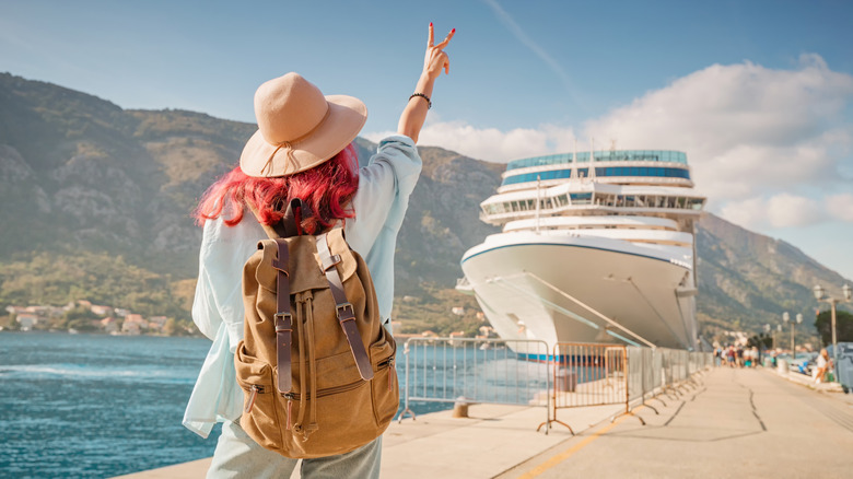 Woman making a peace sign to a cruise ship