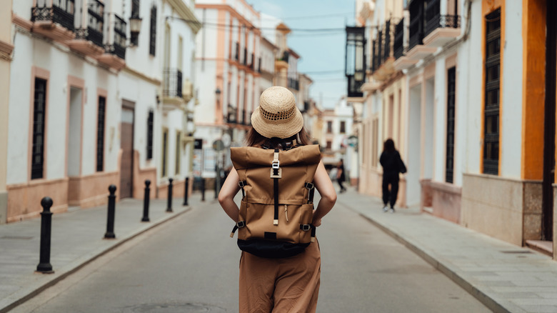 Traveler with a backpack walking down an empty street