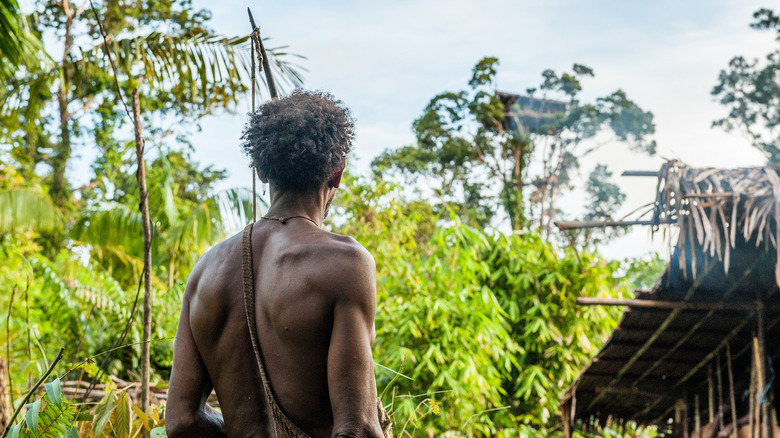 Man with a bow and arrow at Omni Village, Indonesia, home of the Korowai tribe
