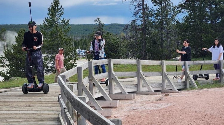 A group of tourists illegally ride across the Yellowstone wooden boardwalks on segways in geothermal areas