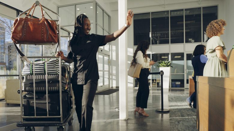 Bellhop waving in busy lobby of American hotel