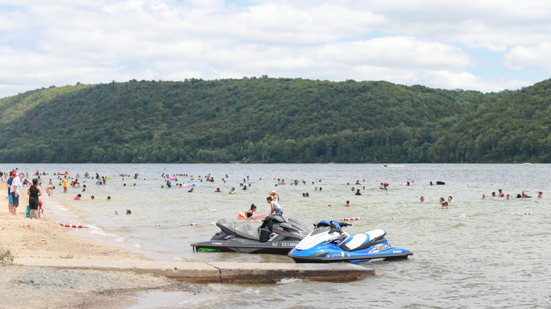 A view of a busy beach at Beltzville State Park, with people swimming and on jet skis.