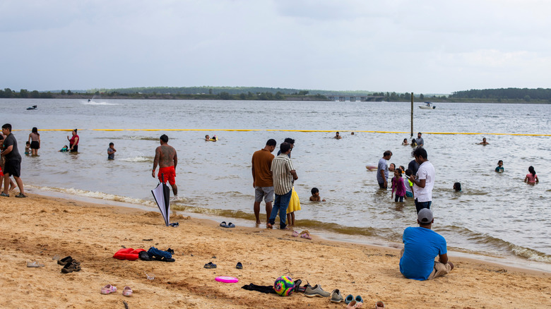 A crowded beach with people on the sand and in the water