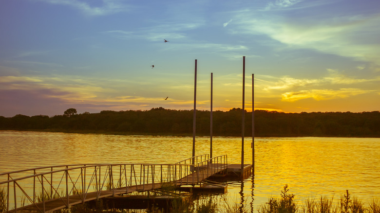 A dock leads into a lake with a sunset overhead