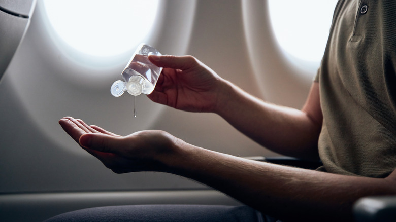 Person using sanitizer on hands inside plane