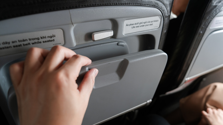Person opening the tray table of an airplane seat