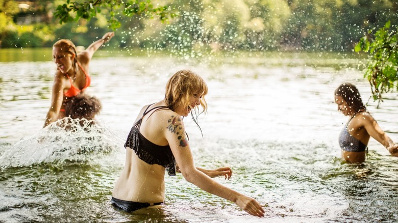 A group of friends splash in a natural body of water