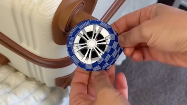 Someone putting a scrunchie on a luggage wheel