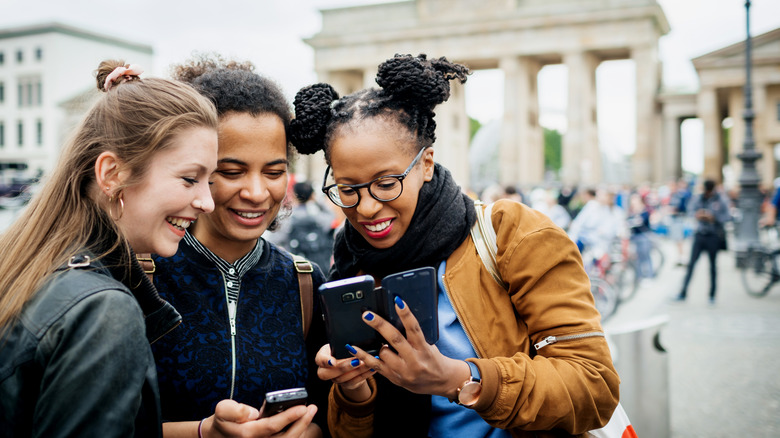 Friends on their phones in front of the Brandenburg Gate in Germany