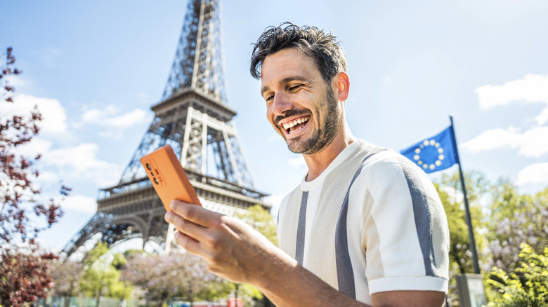 Person using their phone with the Eiffel Tower in the background