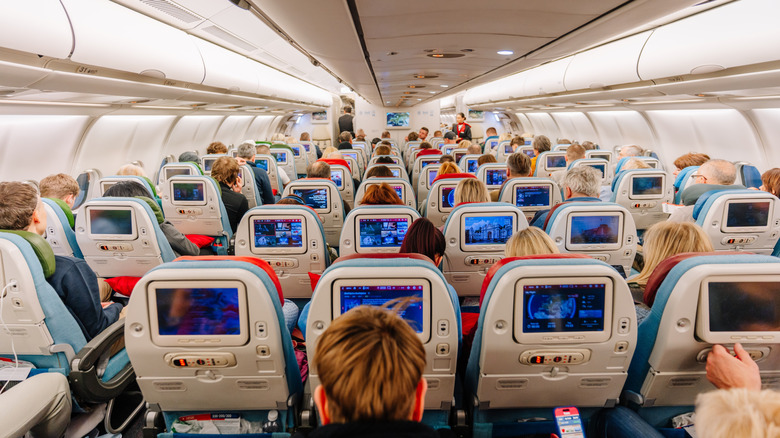 Passengers facing the in-flight entertainment on a busy plane