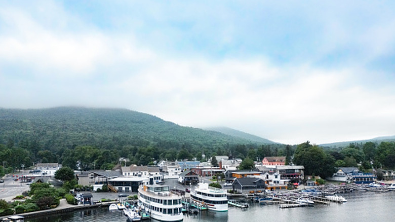 An aerial view of Lake George in New York, with the water in the foreground and foggy mountains behind