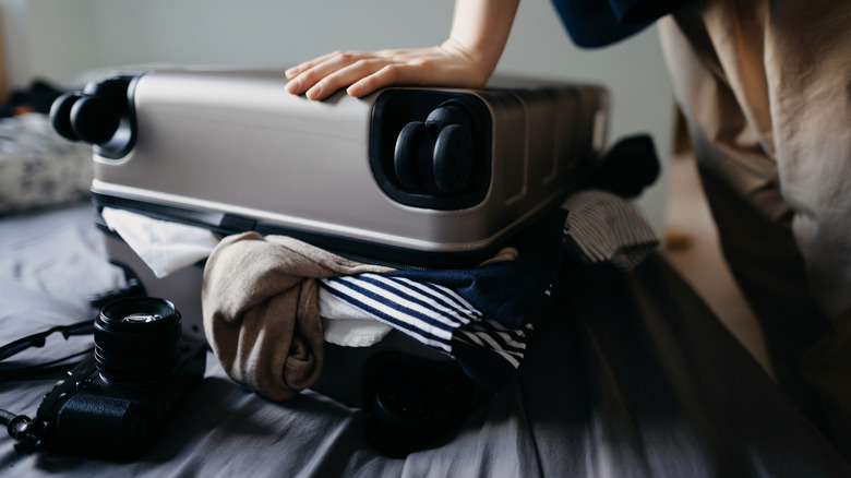 Women pressing down on stuffed luggage