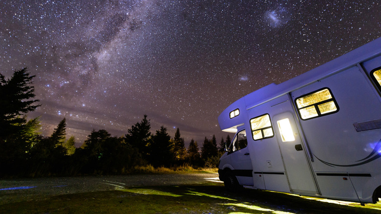 An motorhome parked under a star-filled sky in the wilderness