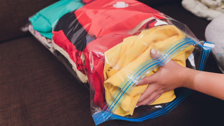 Clothes being packed into a resealable bag.