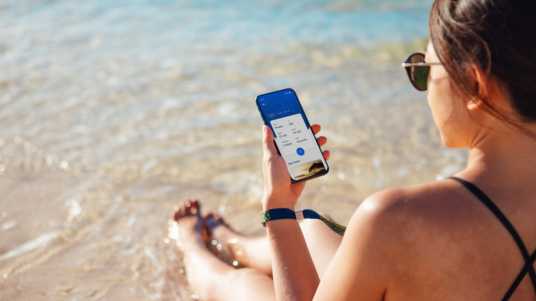 Woman using her phone at the beach.