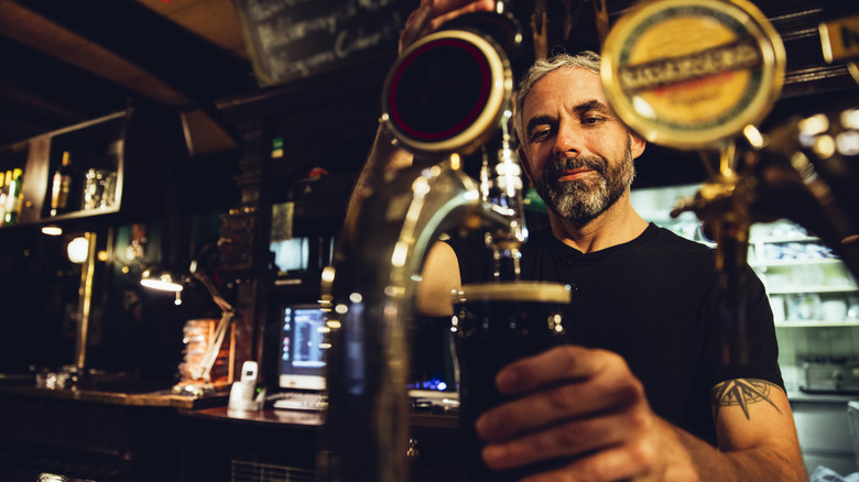 A bartender pouring Guinness from a draught.