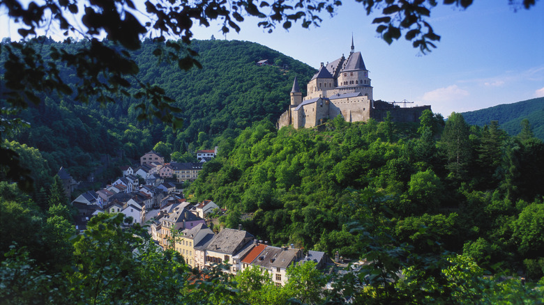 Vianden Castle on a lush hill overlooking a small, hilly town in Luxembourg