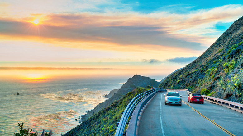 Cars drive along Pacific Coast Highway at sunset