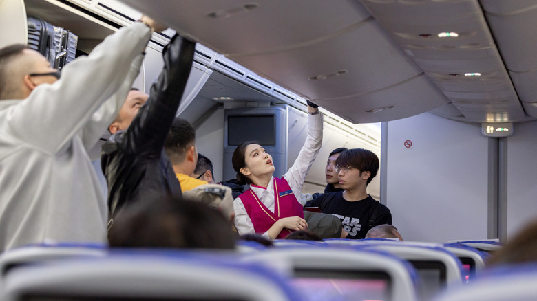 Passengers storing carry-on luggage on a plane