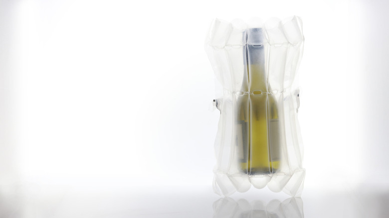 Bottle of white wine inside a reusable wine travel sleeve for safe transportation.