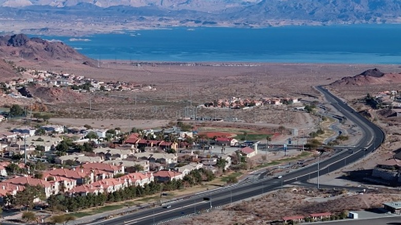 A drone view of a highway through Boulder City, Nevada, in the foreground, and Lake Mead in the background