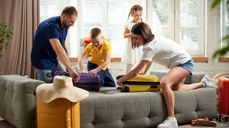 Family unzips suitcases in hotel room