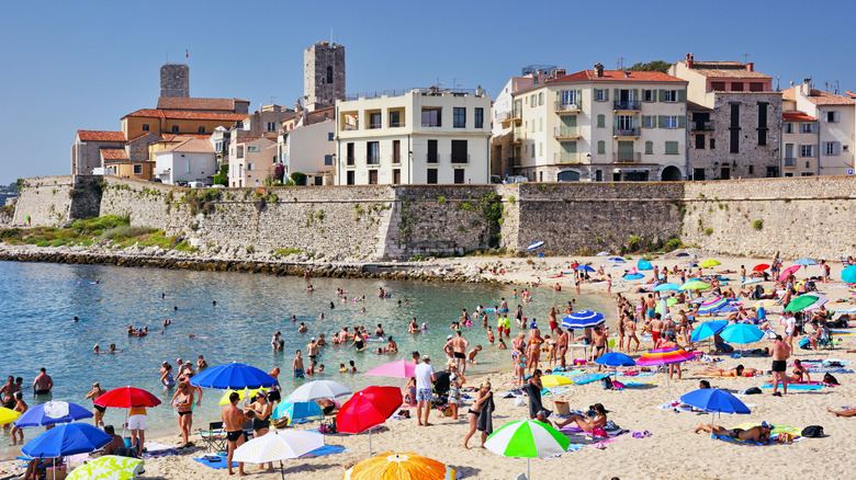 A busy beach in Antibes on a sunny day with colorful umbrellas