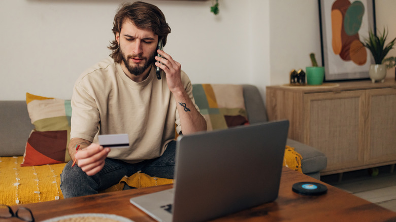 Man on the phone looking at his credit card