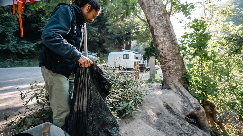 RV camper holding trash bag while cleaning campsite