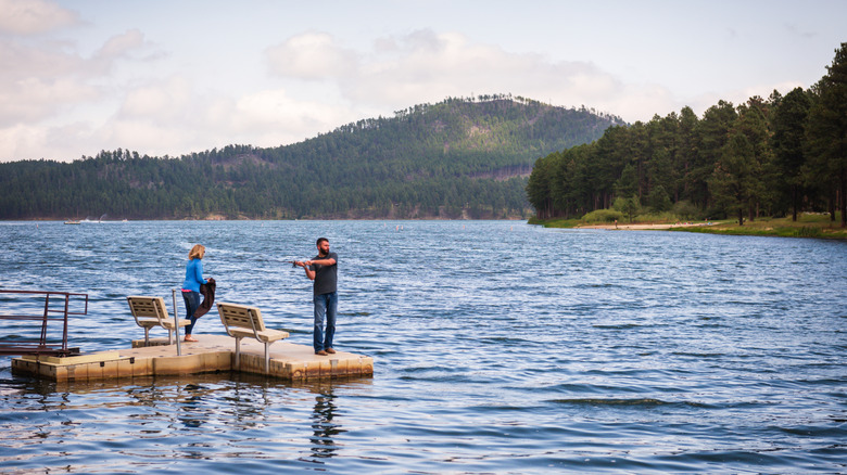 Man and woman fishing in lake with mountains